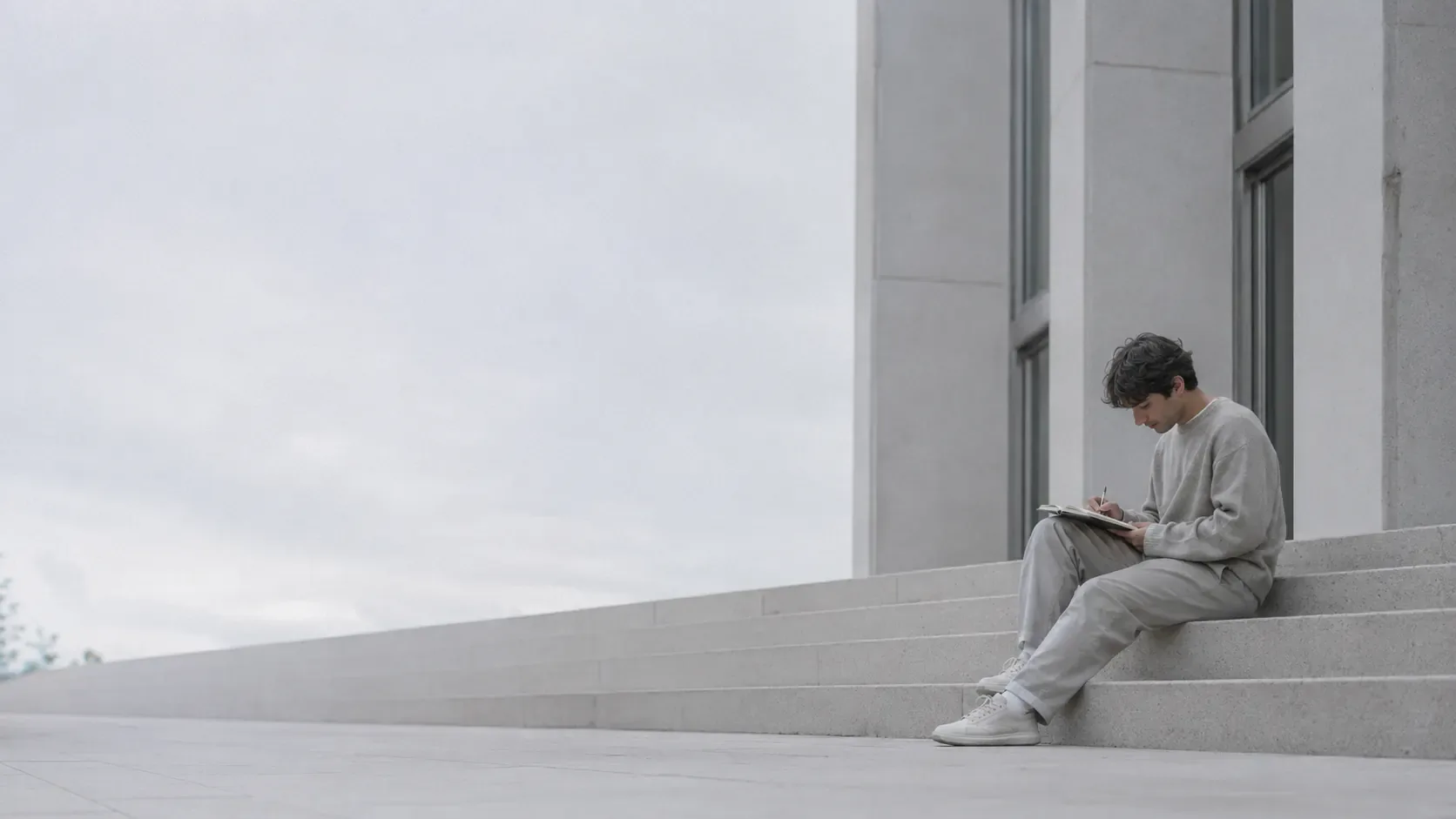 A student sitting with a notebook on a sunny university campus